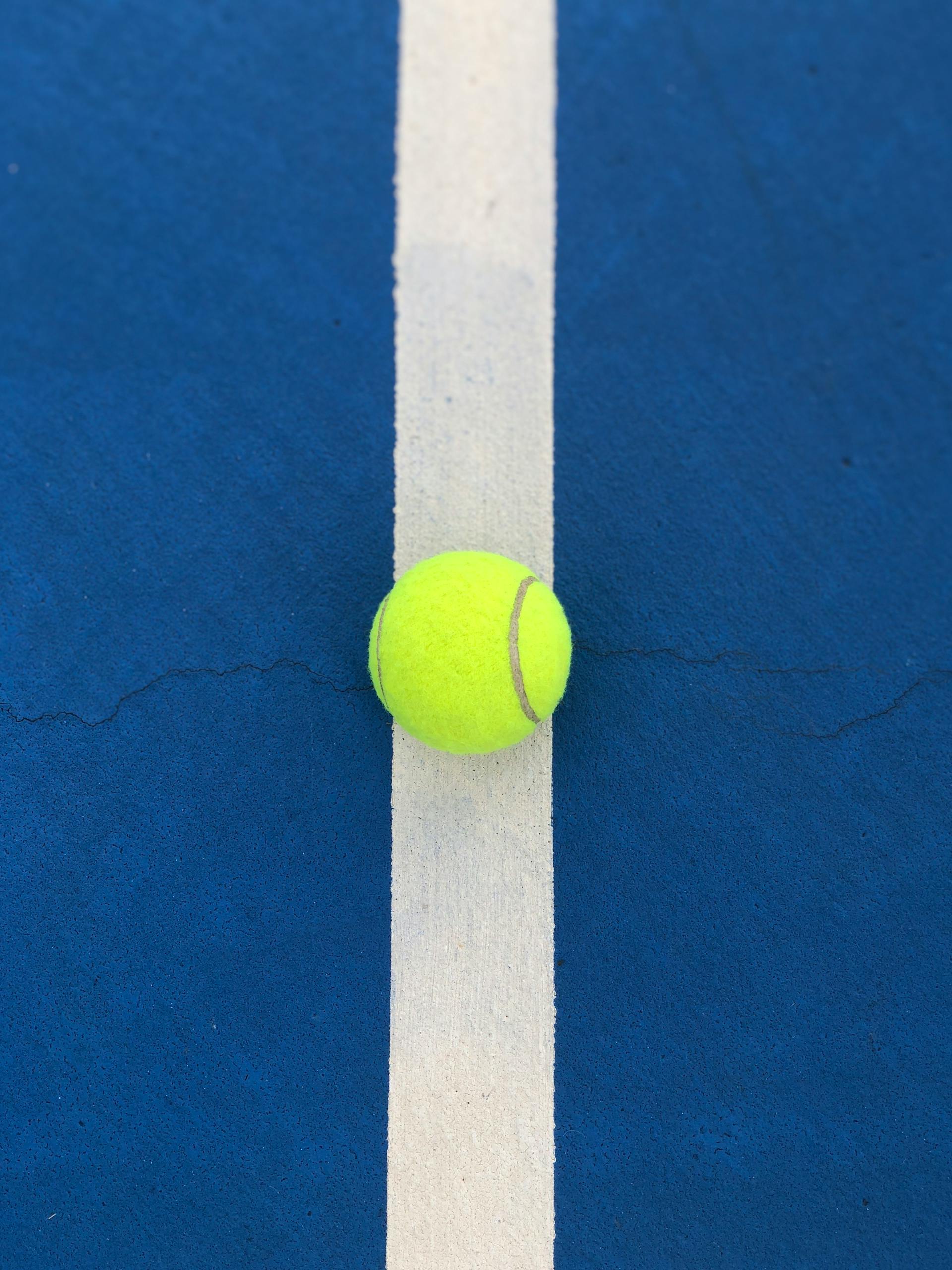 leçon privée au parc Lafontaine Yellow tennis ball perfectly placed on a blue court line, symbolic of precision.