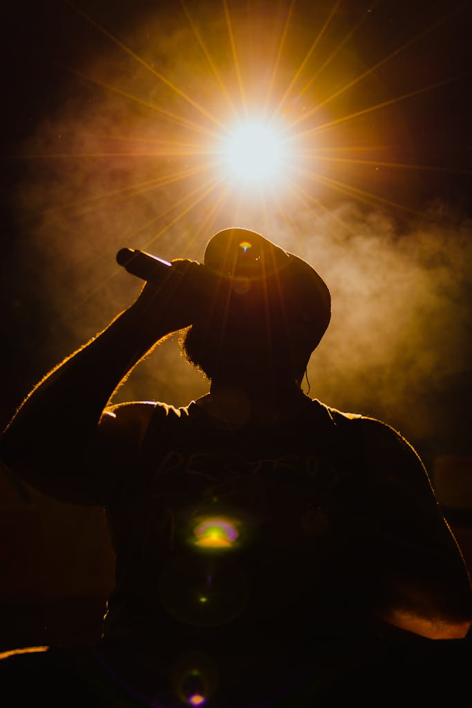 Dramatic silhouette of a singer with a microphone under a bright spotlight.
